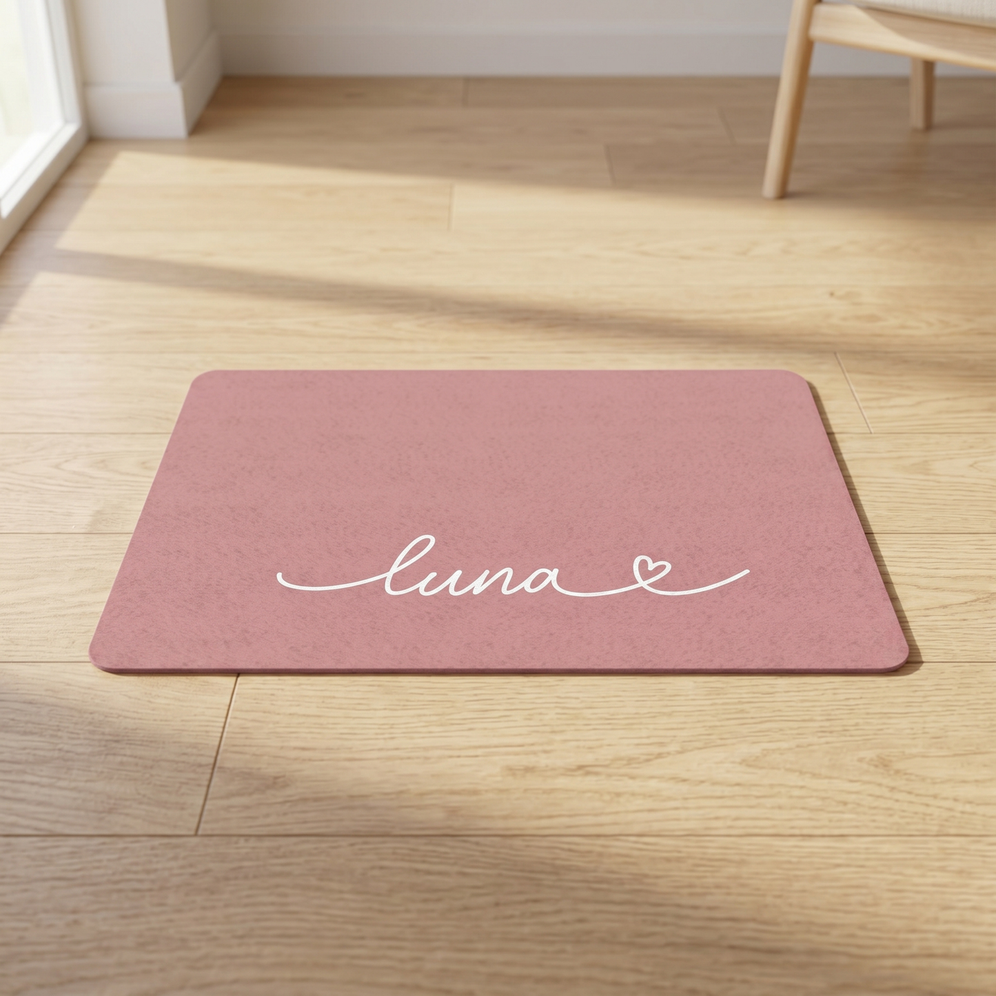 Pink doormat with 'luna' printed on it on a wooden floor.