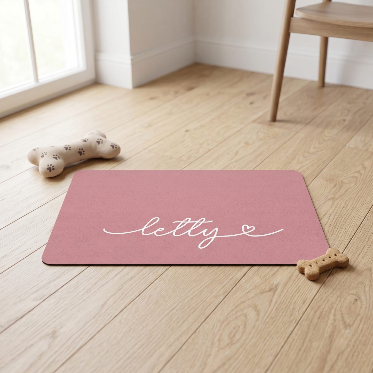Pink mat with 'letty' branding on a wooden floor with dog toys.