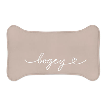 Small beige bone-shaped personalized pet feeding mat with the name Bogey in white script