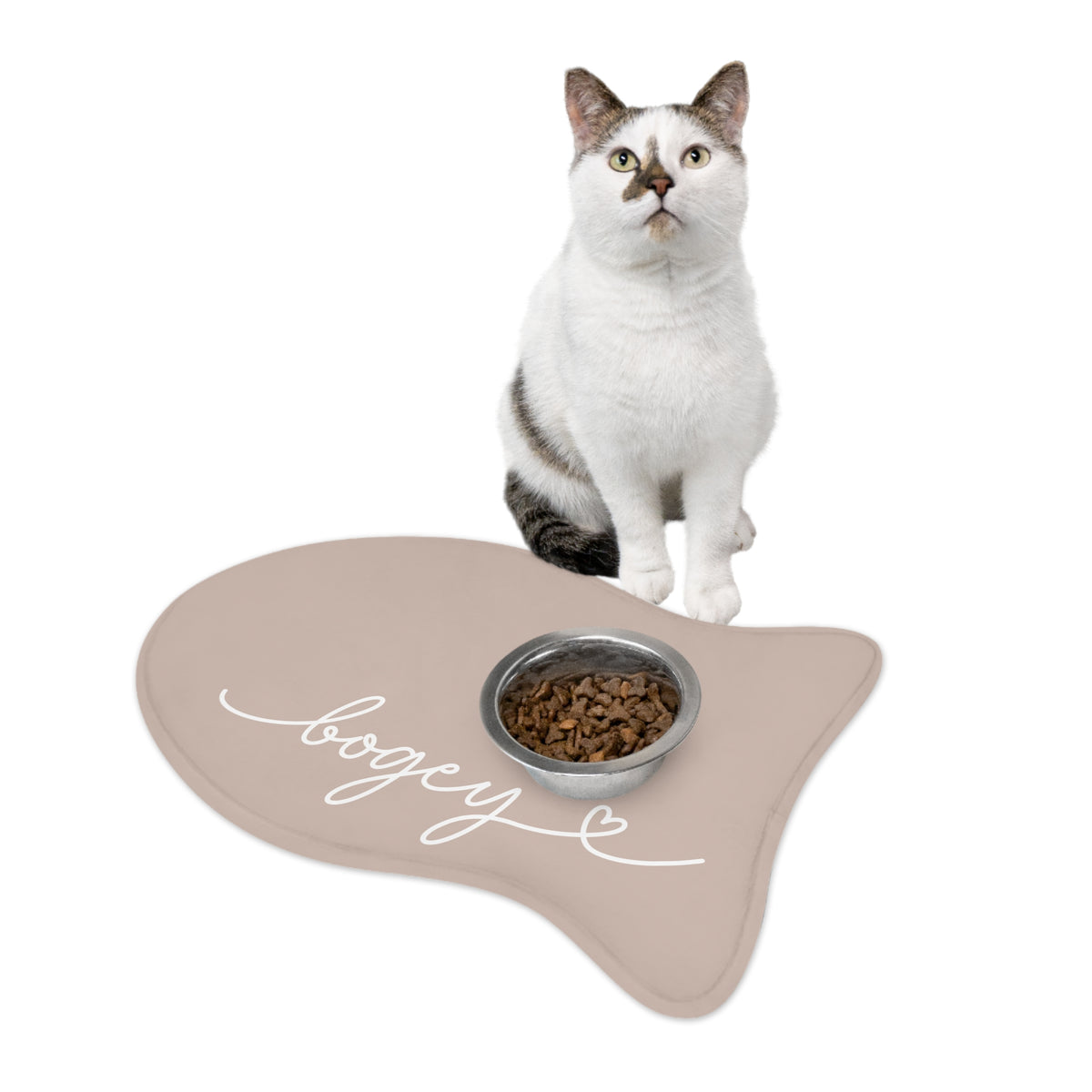 Cat sitting on a beige fish-shaped personalized pet feeding mat next to a food bowl