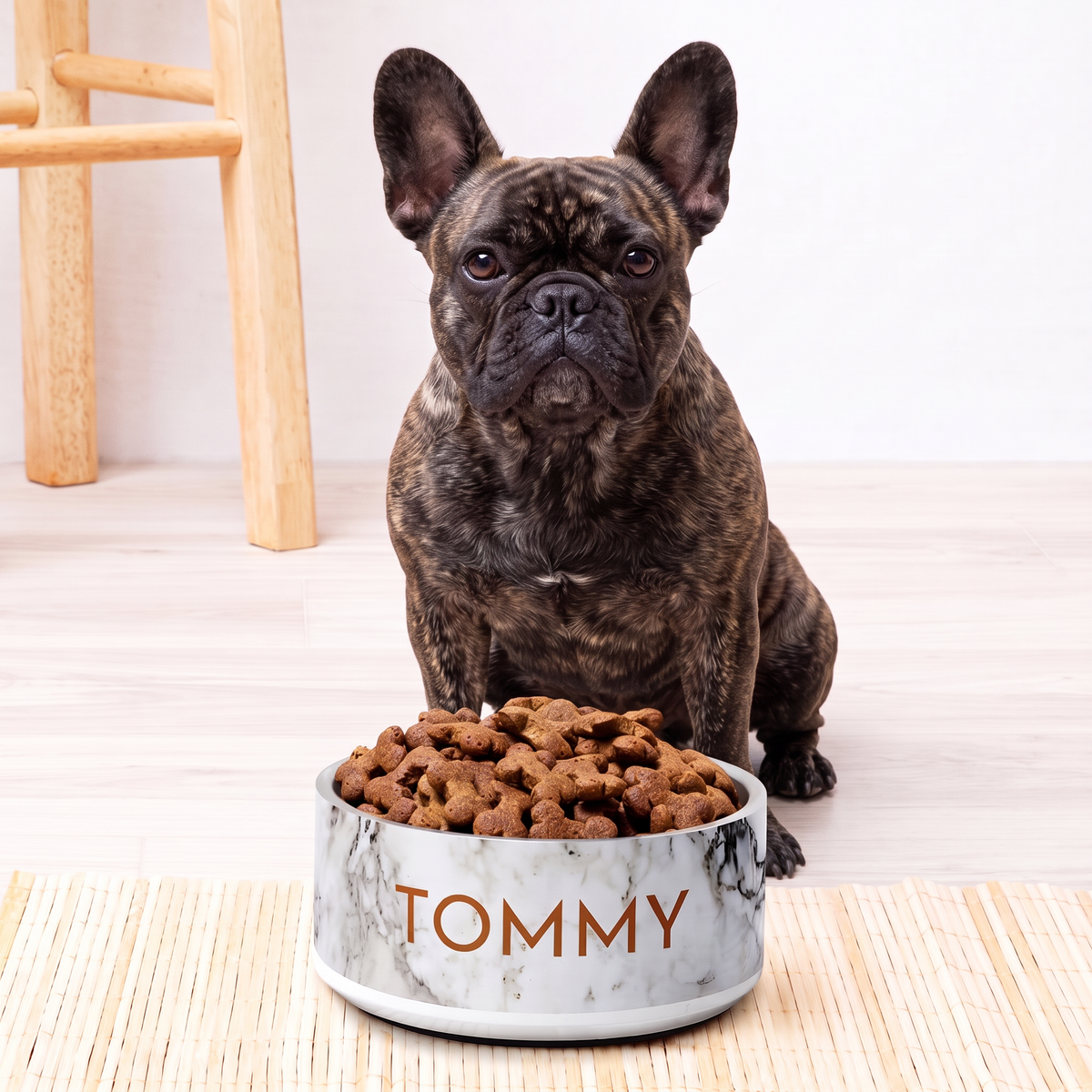 French bulldog sitting behind a black and gold marble personalized dog bowl filled with kibble