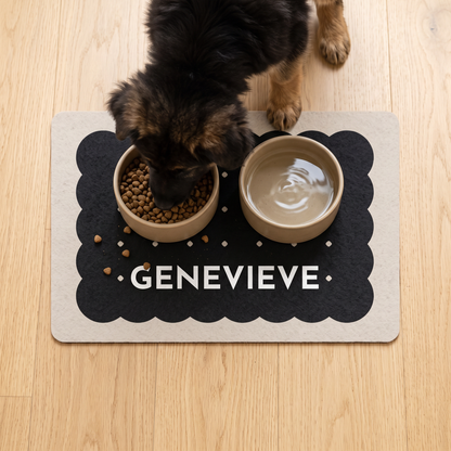 Dog eating from a bowl on a black biscuit personalized dog food mat with the name Genevieve