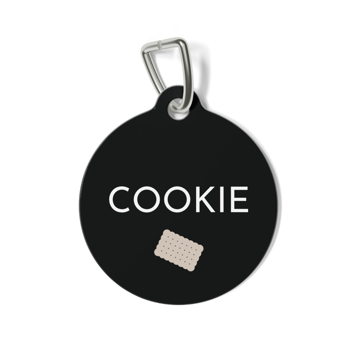Round black biscuit personalized dog tag with the name Cookie in white capitals and a small sand scalloped biscuit