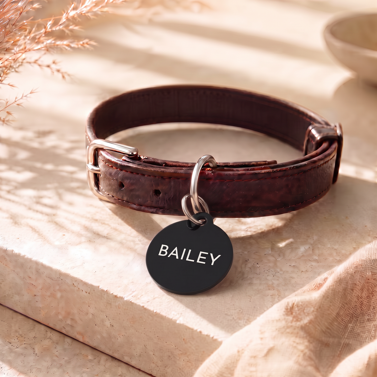Black modern personalized dog tag on a brown leather collar on linen