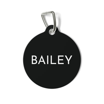 Round black modern personalized dog tag with the name in clean white capital letters