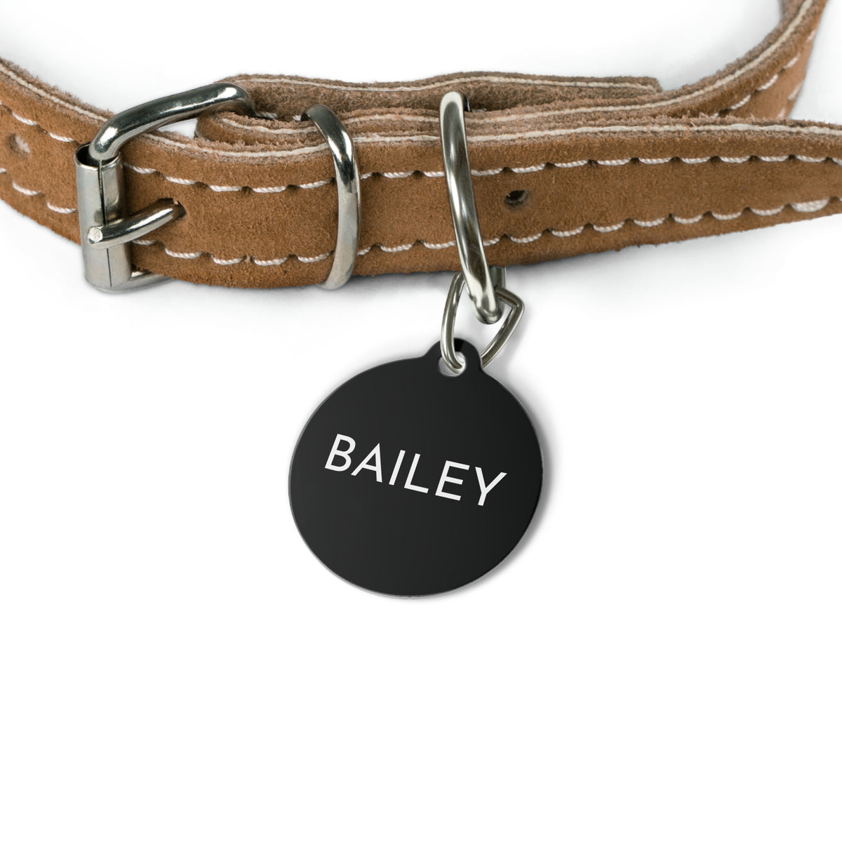 Black modern personalized dog tag hanging from a tan leather dog collar