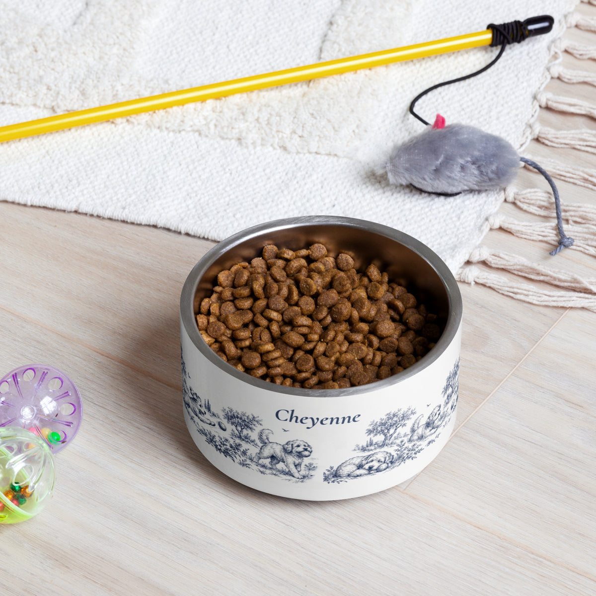 Blue dog toile personalized dog bowl filled with kibble on a rug next to a pet toy