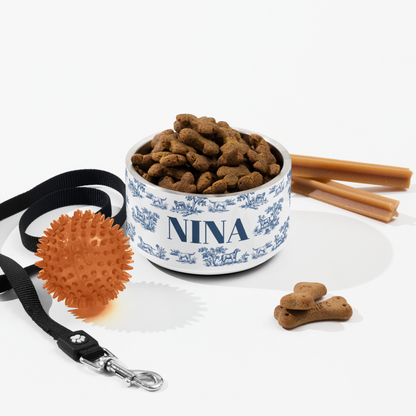 Flat lay of an 18 oz blue toile personalized dog bowl with kibble, a leash, a ball and dog treats