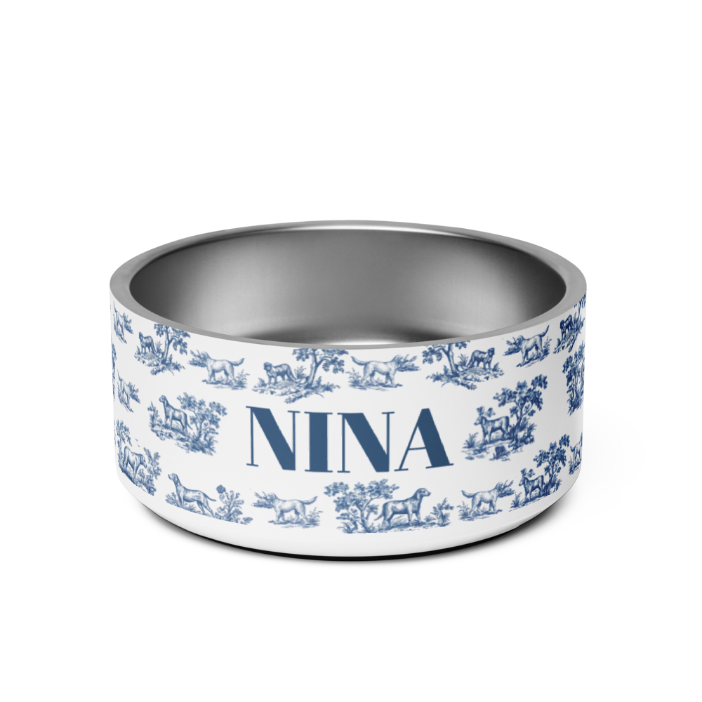 Blue toile personalized dog bowl with the name Nina in bold navy serif lettering on a white toile de Jouy print with hounds and trees
