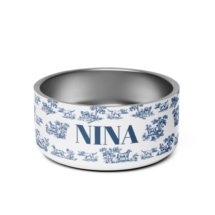 Blue toile personalized dog bowl with the name Nina in bold navy serif lettering on a white toile de Jouy print with hounds and trees