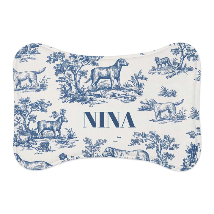 Blue toile bone-shaped personalized pet feeding mat with dogs in a classic toile landscape and the name Nina