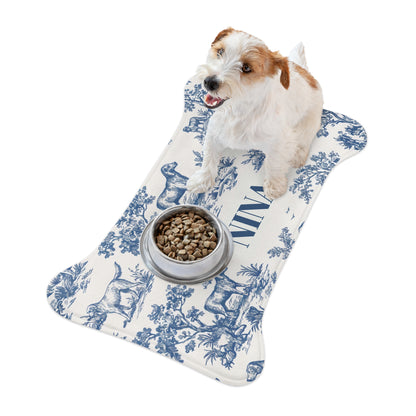 Jack Russell terrier standing on a blue toile bone-shaped personalized pet feeding mat next to a food bowl