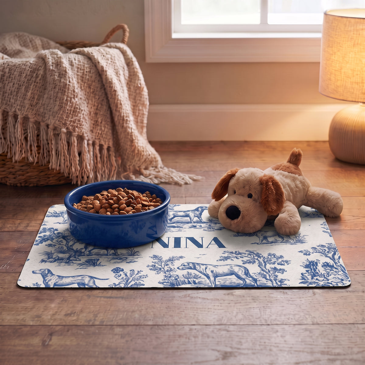 Blue toile personalized pet food mat with a food bowl and a plush dog toy in a cozy room