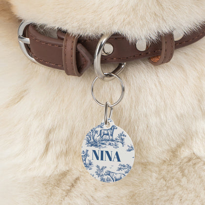 Blue toile pet tag hanging from a dark brown leather collar on a fluffy dog