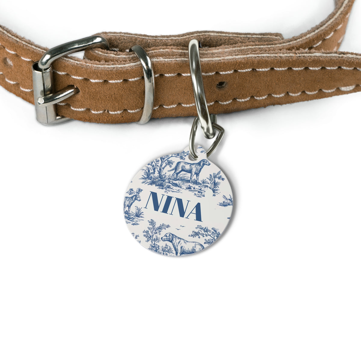 Blue toile name tag attached to a tan leather dog collar