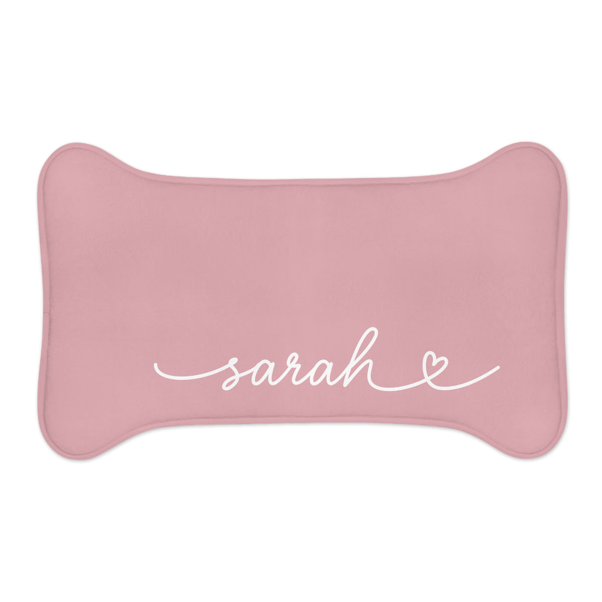 Small blush pink bone-shaped personalized pet feeding mat with the name Sarah in white script