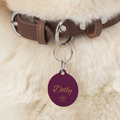 Close-up of the burgundy crown pet tag hanging from a brown collar on a fluffy dog