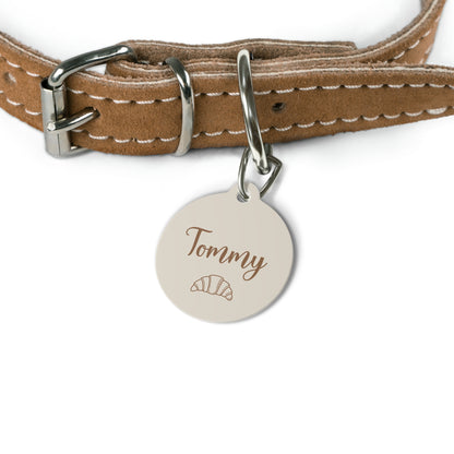 Croissant name tag attached to a tan leather dog collar