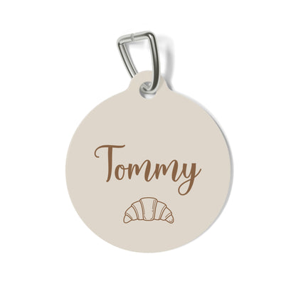 Cream personalized pet tag with the name Tommy in script and a small croissant