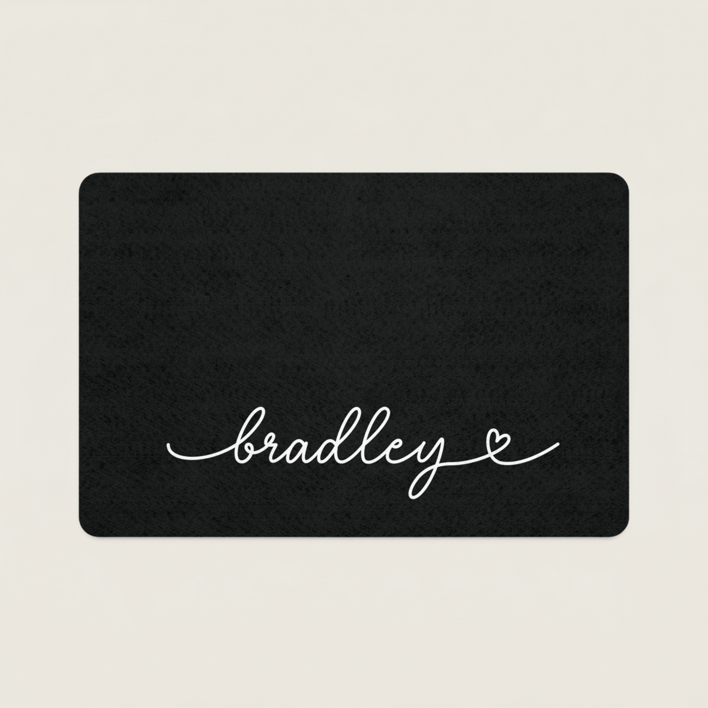 Black dog food mat with 'bradley' in cursive on a beige background