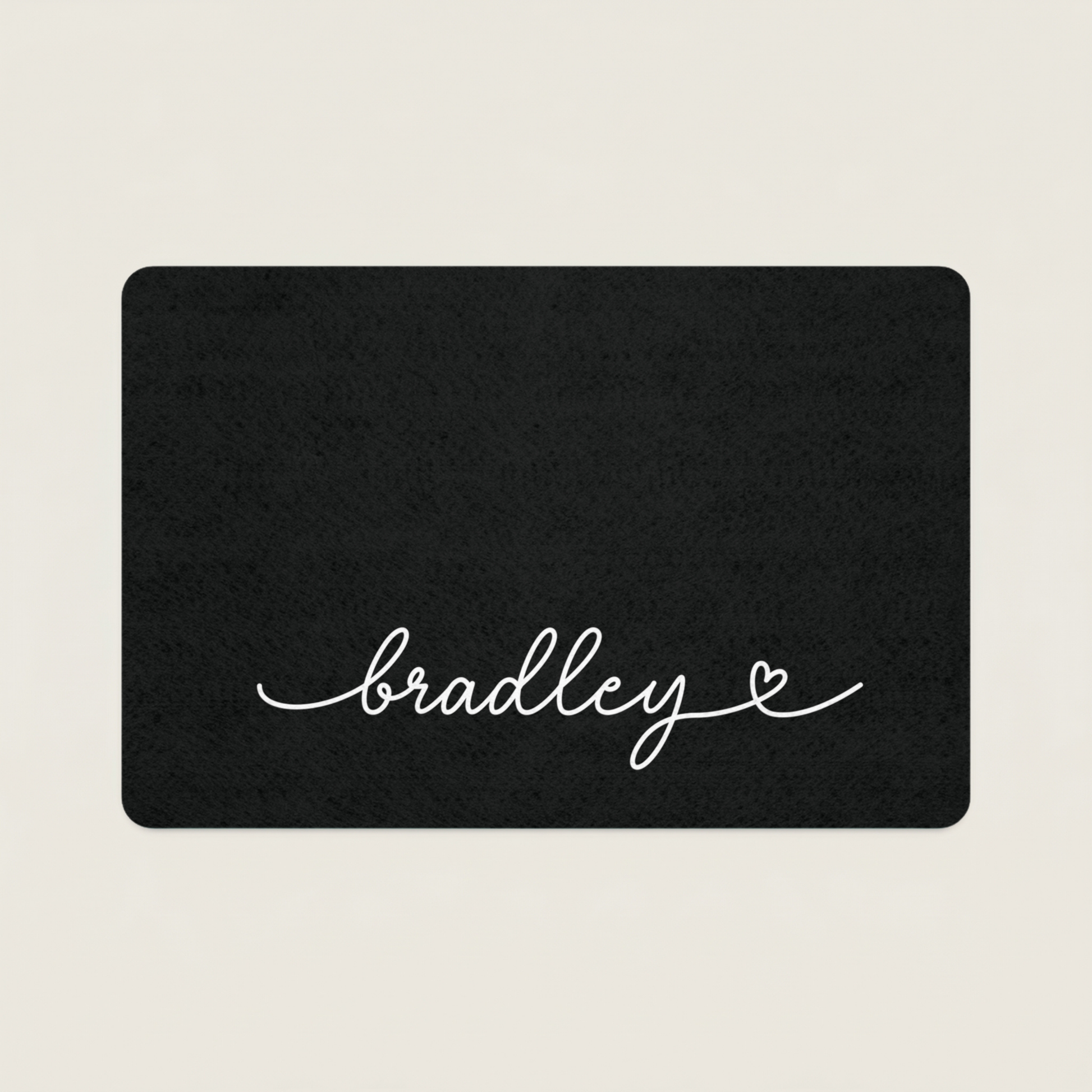 Black dog food mat with 'bradley' in cursive on a beige background