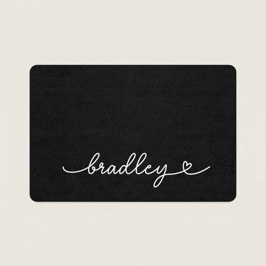 Black dog food mat with 'bradley' in cursive on a beige background