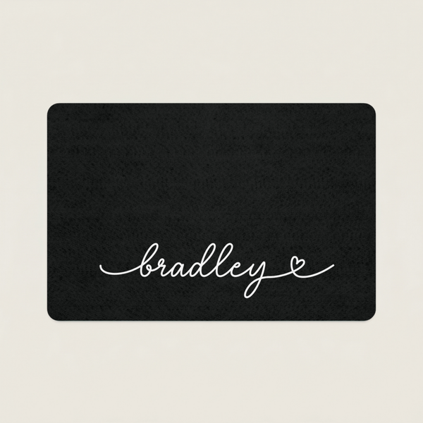 Black dog food mat with 'bradley' in cursive on a beige background