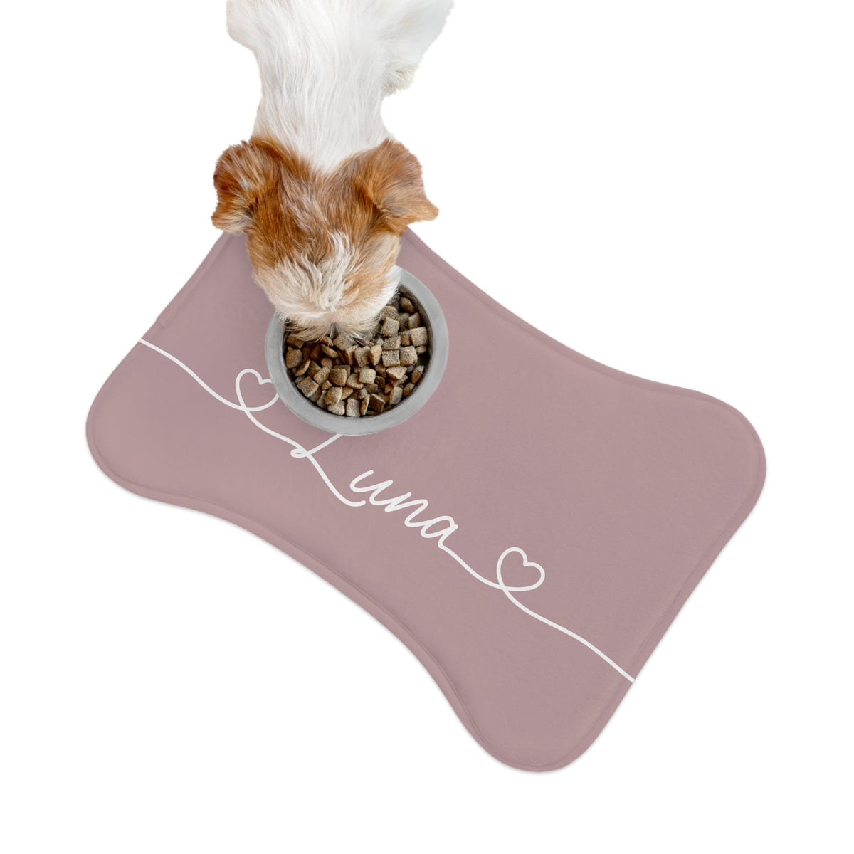 Dog eating from a bowl on a dusty rose bone-shaped personalized feeding mat, seen from above