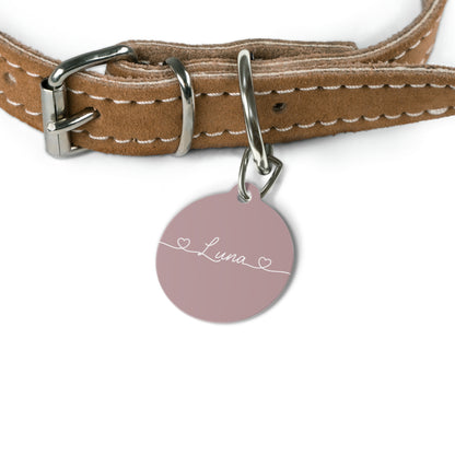 Dusty rose personalized pet tag hanging from a tan leather dog collar