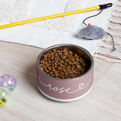 Dusty rose personalized dog bowl with kibble on the floor next to a dog toy