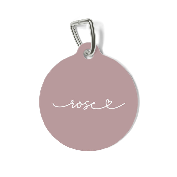 Round dusty rose personalized pet tag with the name Rose in white handwritten script and a small heart