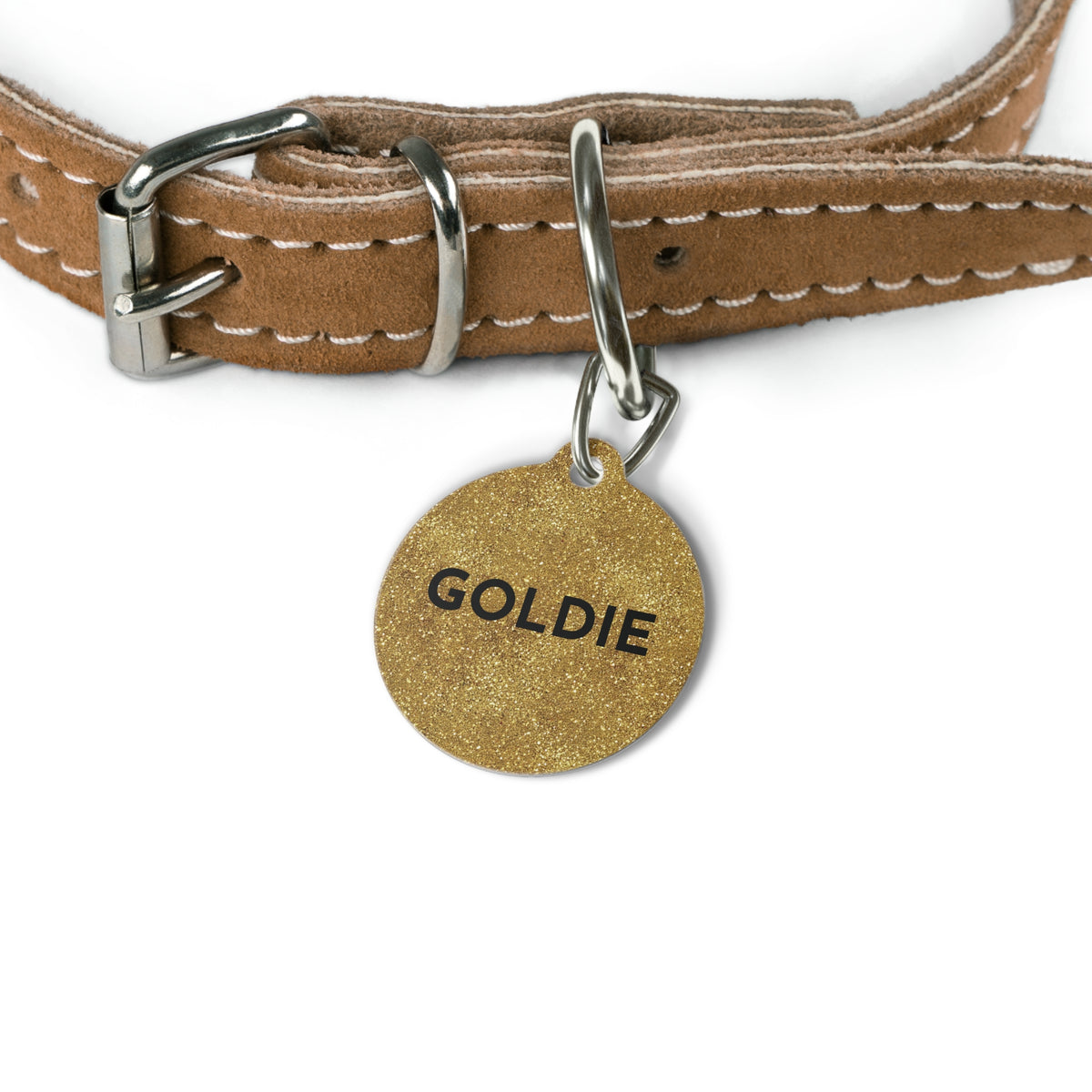 Gold glitter personalized dog tag hanging from a tan leather dog collar