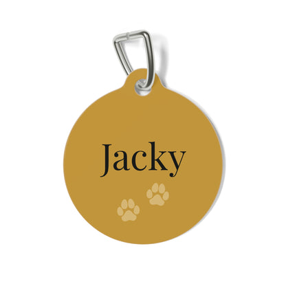 Round gold personalized dog tag with the name Jacky in dark serif lettering and two paw prints