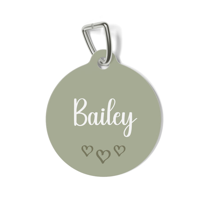 Sage green heart personalized pet tag with the name Bailey in white script and three small hearts