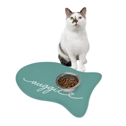 White cat sitting on a jade fish-shaped personalized pet feeding mat next to a food bowl