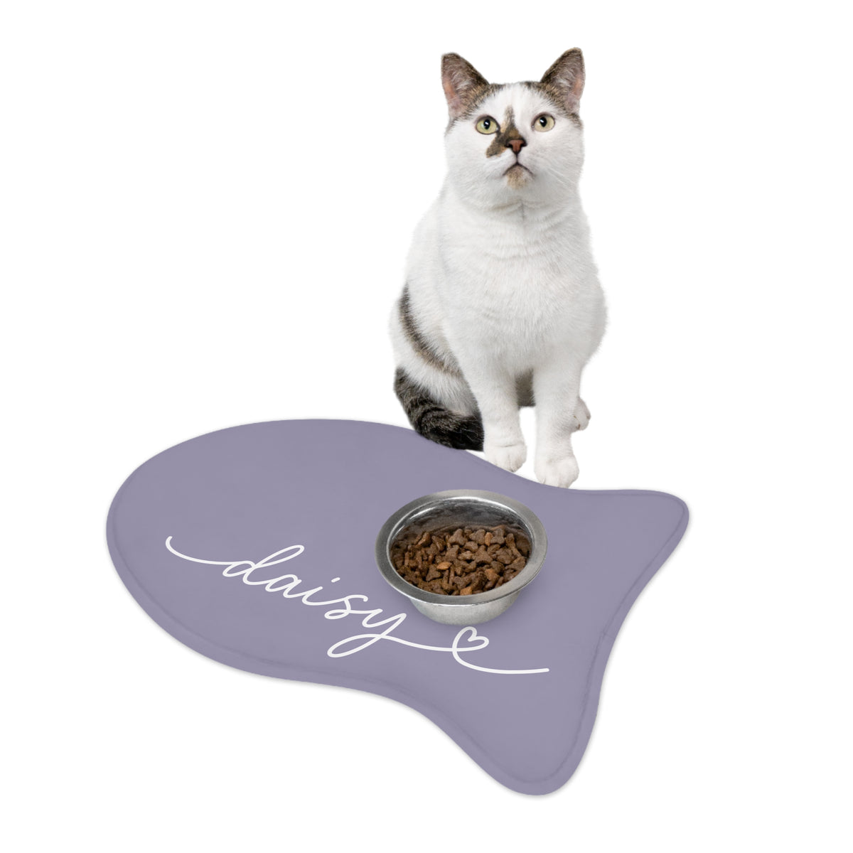 Cat sitting on a lavender fish-shaped personalized pet feeding mat next to a food bowl