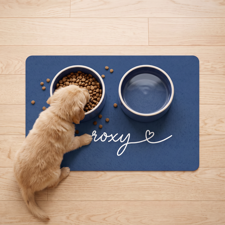 Puppy eating from a bowl on a midnight blue personalized pet food mat with the name Roxy