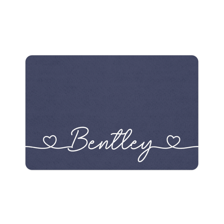 Navy blue rectangle personalized pet food mat with the name Bentley in white handwritten script framed by two hearts