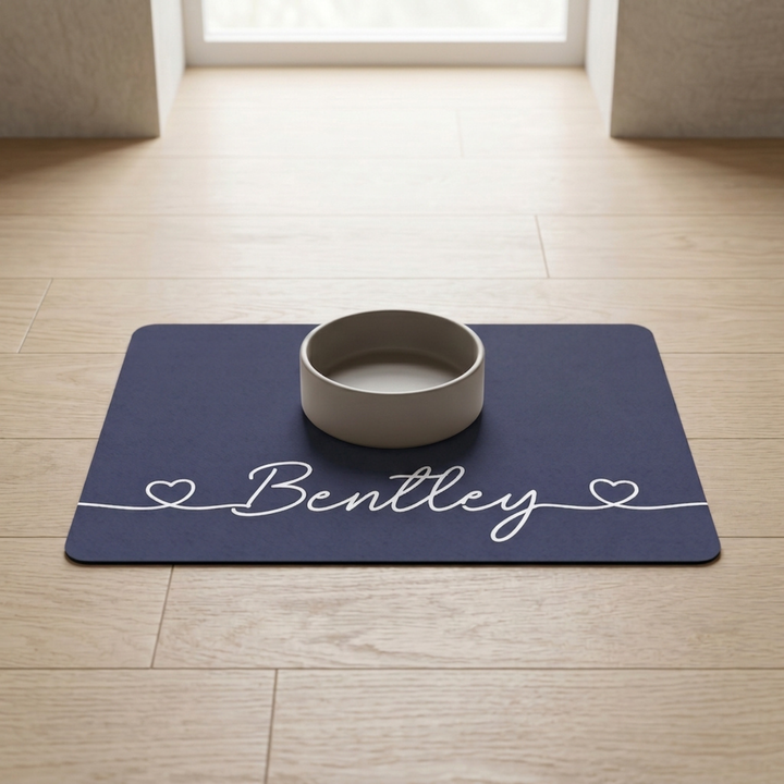Navy blue personalized pet food mat with the name Bentley and a bowl in a bright room