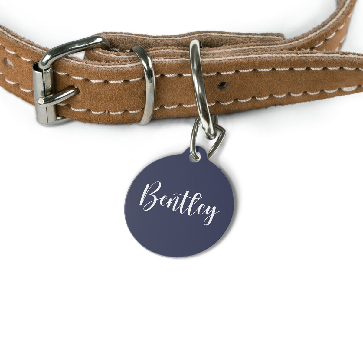 Navy blue personalized pet tag hanging from a tan leather dog collar