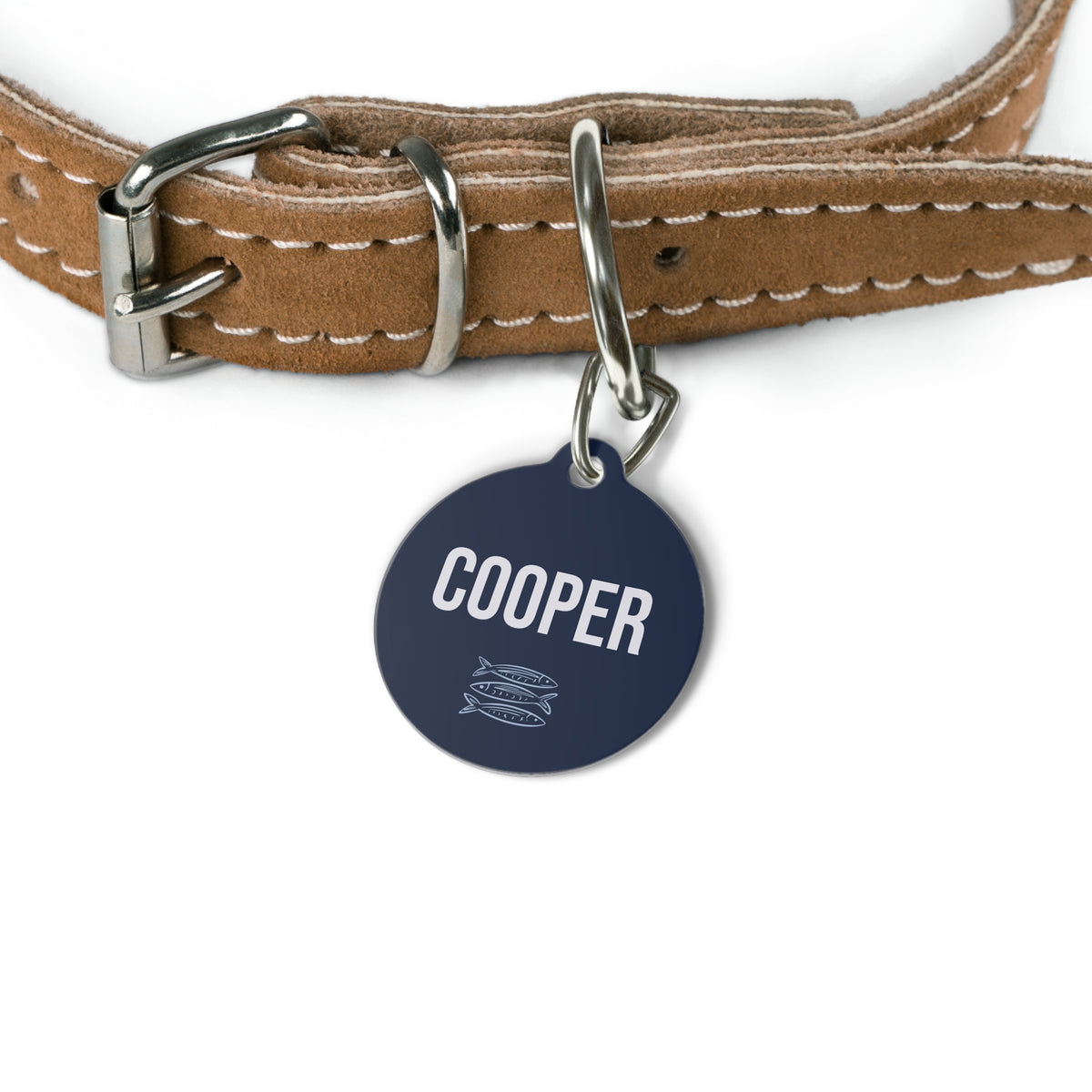 Navy sardine name tag attached to a tan leather dog collar