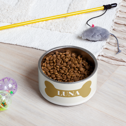 Off-white gold bone personalized dog bowl filled with kibble on a rug next to dog toys