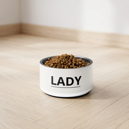 Off-white modern personalized dog bowl with the name Lady filled with kibble on a light wooden floor