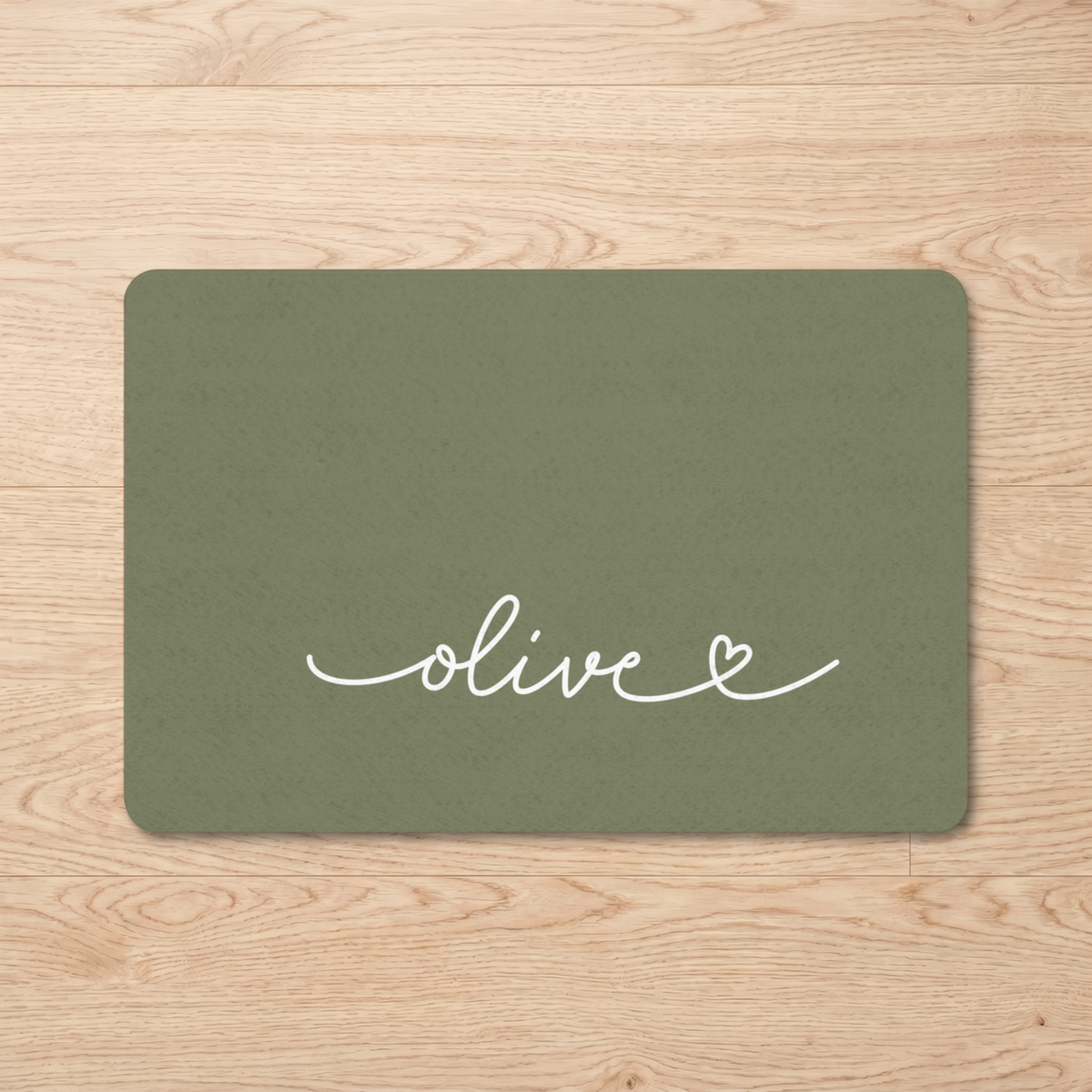 Olive green personalized pet food mat with the name Olive on a wooden floor