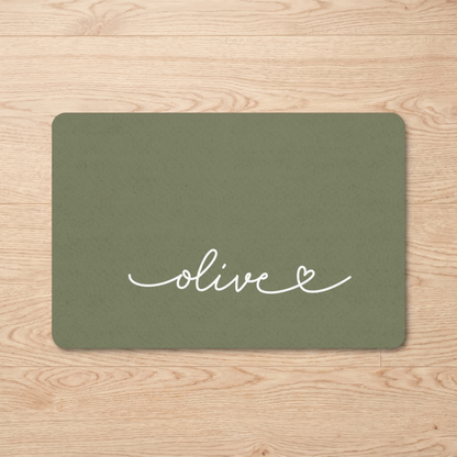 Olive green personalized pet food mat with the name Olive on a wooden floor