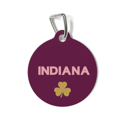 Burgundy personalized dog tag with the pet name in light lettering and a gold clover