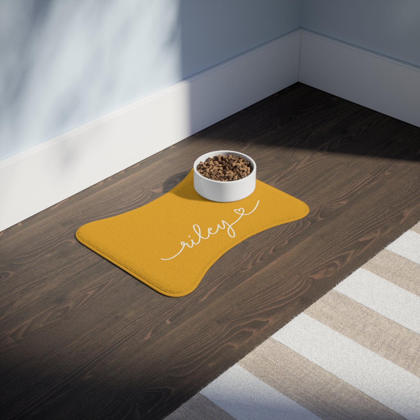 Personalized marigold dog food mat with a feeding bowl on a dark wood table - lifestyle