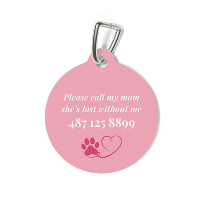 Back of the pink pet ID tag with printed contact details and a small paw print