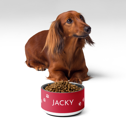 Dachshund next to a red paw print personalized dog bowl filled with kibble