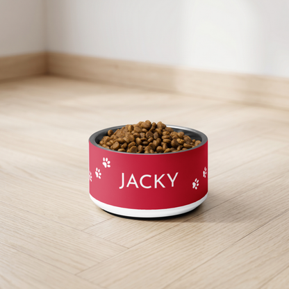 Red personalized dog bowl with the name Jacky and kibble on a light floor